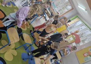 Przedszkolaki sprzątają krzesełka poprzestawiane w Sali przez złośliwego skrzata.