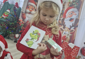 Alicja wyjmuje z koperty kolejne zadanie pozostawione przez Grincha.