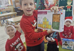 Franuś pokazuje do zdjęcia klocki magnetyczne, które dzieci otrzymały od Świętego Mikołaja.