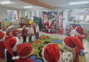 Dzieci stoją na dywanie przed Świętym Mikołajem.