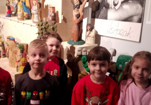 Grupka dzieci pozuje do zdjęcia na tle rzeźb.