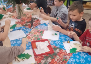 Grupka dzieci maluje choinki.