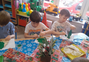 Trójka chłopców maluje choinki.