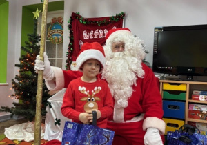 Piotruś pozuje do zdjęcia z Mikołajem.