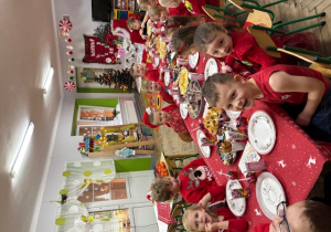 Dzieci siedzą przy stoliczkach podczas poczęstunku.