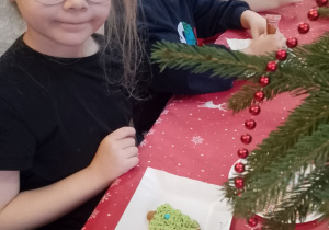 Zuzia prezentuje swój pierniczek w kształcie choinki.