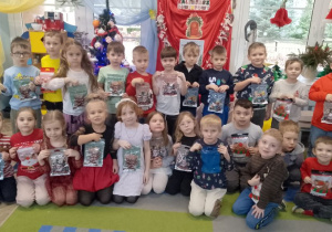 Zdjęcie grupowe dzieci z pierniczkami zapakowanymi w świąteczne torebki.