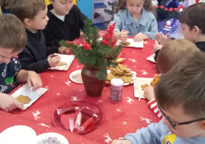 Grupka dzieci podczas pracy ozdabiania pierników.