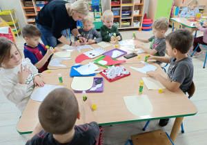 Pani z grupy pomaga Karolowi wykleić kontur postaci.