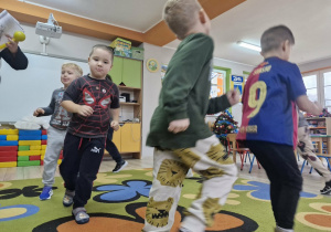 Przedszkolaki biegają po dywanie w trakcie zabawy ruchowej.