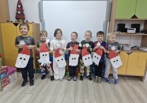 Dzieci pozują do zdjęcia trzymając w dłoniach wykonane przez siebie wizerunki Świętego Mikołaja.