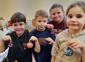 Grupka dzieci prezentuje udekorowane przez siebie bombki.