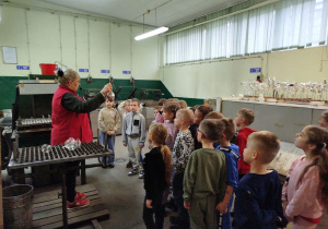 Pani podniosła bombkę do góry i opowiada dzieciom na czym polega srebrzenie bombek.