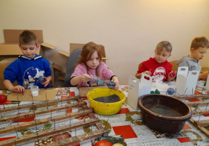 Czworo dzieci dekoruje bombki podczas zajęć.