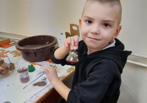 Jakub siedzi przy stole i prezentuje swoją bombkę.