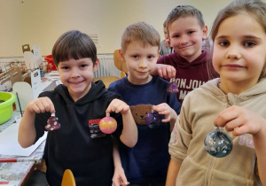 Czworo dzieci prezentuje wykonane przez siebie bombki.