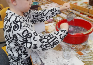 Fabian obsypuje swoją bombkę brokatem.