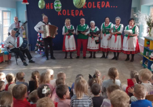 Dzieci słuchają kolęd śpiewanych przez zaproszonych gości.