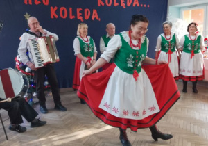 Pani z zespołu prezentuje dzieciom strój ludowy.