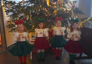 Tosia, Nadia, Marysia i Emma pozują do zdjęcia na tle choinki. Dziewczynki trzymają certyfikaty.