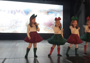 Zespół "Słoneczka" śpiewa na scenie piosenkę świąteczną. Dziewczynki trzymają mikrofony w rękach.