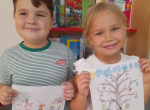 Julek i Tosia stoją obok siebie z wykonanymi pracami na konkurs "Książka leczy duszę i ciało". W tle kącik książki.