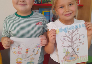 Julek i Tosia stoją obok siebie z wykonanymi pracami na konkurs "Książka leczy duszę i ciało". W tle kącik książki.