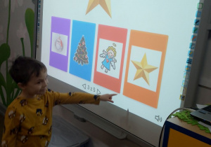 Bartek stoi przy tablicy multimedialnej i wskazuje obrazek z gwiazdką.