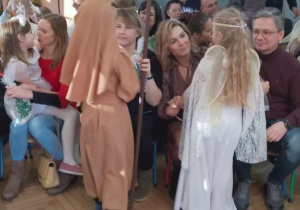 Dzieci wręczają rodzicom upominki i składają życzenia.