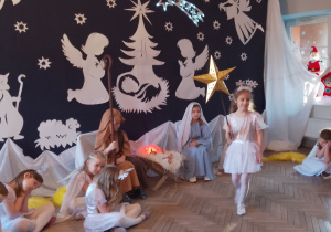 Na środek sceny wchodzi Amanda z gwiazdą w ręku. Z boku śpią Aniołki i Gwiazdki. Maryja i Józef siedzą przy żłóbku. W tle dekoracja.