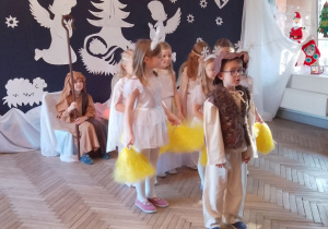 Mikołaj przebrany za pastuszka stoi przed Gwiazdkami i Aniołkami. Chłopiec prezentuje kolejny fragment inscenizacji.