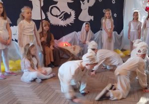 Czterech chłopców w roli Baranków idzie na kolanach w małym kółeczku.