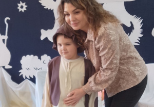 Julek pozuje do zdjęcia z mamą na tle jasełkowej dekoracji.