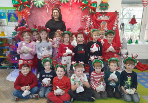 Dzieci pozują do wspólnego zdjęcia z mamą Nadii. Przedszkolaki trzymają mikołajkowe niespodzianki otrzymane od zaproszonego gościa.