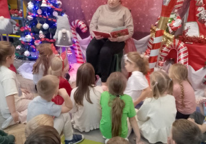 Pani Karolina - logopeda czyta dzieciom książkę o tematyce świątecznej.
