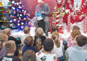Dzieci siedzą na dywanie, a Pan Łukasz - pracownik sekretariatu prezentuje dzieciom książkę pt. "Najpiękniejsze opowieści pod choinkę".