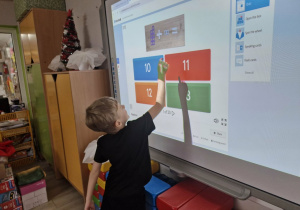 Oluś dodaje klocki Numicon na tablicy multimedialnej.