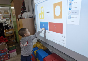 Szymek dodaje klocki Numicon na tablicy multimedialnej.