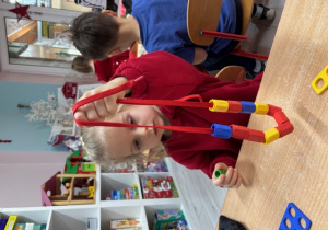 Marysia nawleka klocki na sznurek.