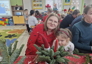 Klara z mamą siedzą przy stole i tworzą świąteczny stroik.