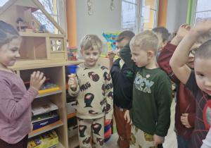 Olek trzyma w dłoni niebieski dzwoneczek. Wokół stoją inne dzieci z grupy.