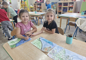 Majka i Lilianka siedzą przy stoliku i kolorują fragmenty dużej kolorowanki z wizerunkiem Grincha.