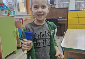 Wojtuś trzyma w dłoni dzwoneczek schowany przez Grincha w zabawkach dzieci.