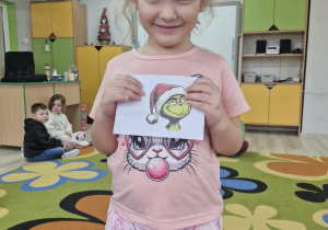 Klara trzyma w dłoniach kopertę z obrazkiem Grincha.