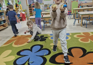 Dzieci sprzątają rozrzucone przez Grincha kredki i bombki. Franek pokazuje do zdjęcia bombki zebrane z dywanu.