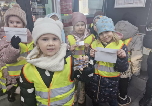 Przedszkolaki trzymają w dłoniach koperty i magnesy zakupione na poczcie.