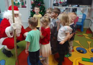 Mikołaj podczas rozmowy z grupą Pszczółek. Z tyłu świąteczna choinka.