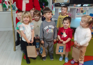 Mikołaj i dzieci z prezentami pozują do zdjęcia.