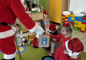 Mikołaj rozdaje prezenty dzieciom z grupy Biedronek.
