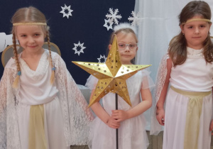 Trzy dziewczynki stoją obok siebie. Nikola i Nadia w strojach Aniołków, a w środku Zuzia jako Gwiazdka.